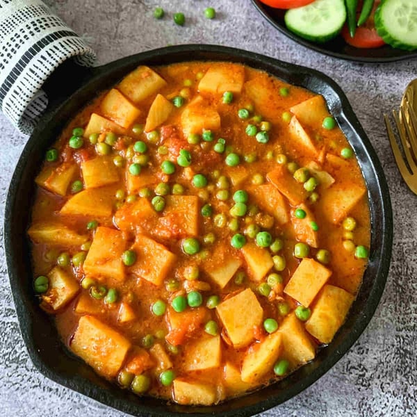 Aloo Matar, an Indian potato and pea curry, in a black cast iron pan.