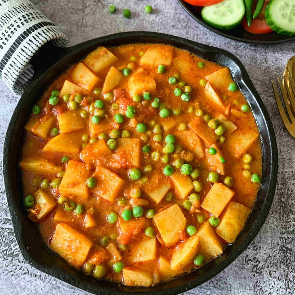Aloo Matar, an Indian potato and pea curry, in a black cast iron pan.