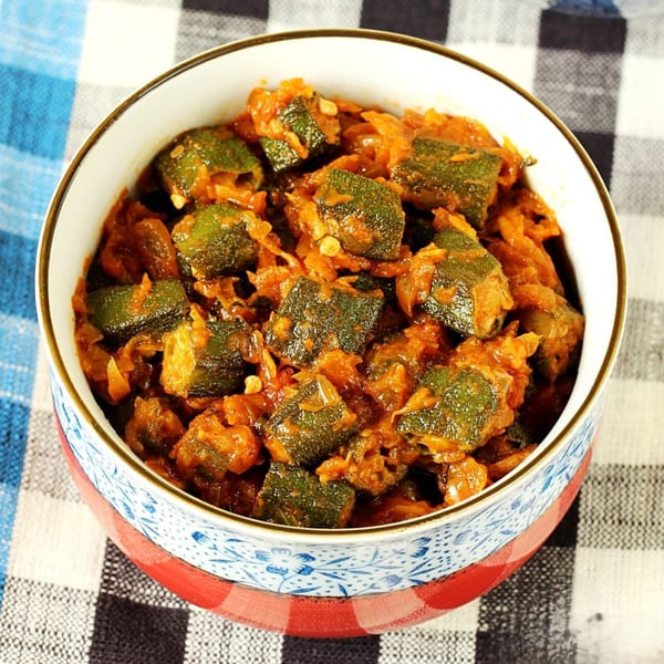 A bowl of Bhindi Masala, an Indian okra curry, on a checkered tablecloth.